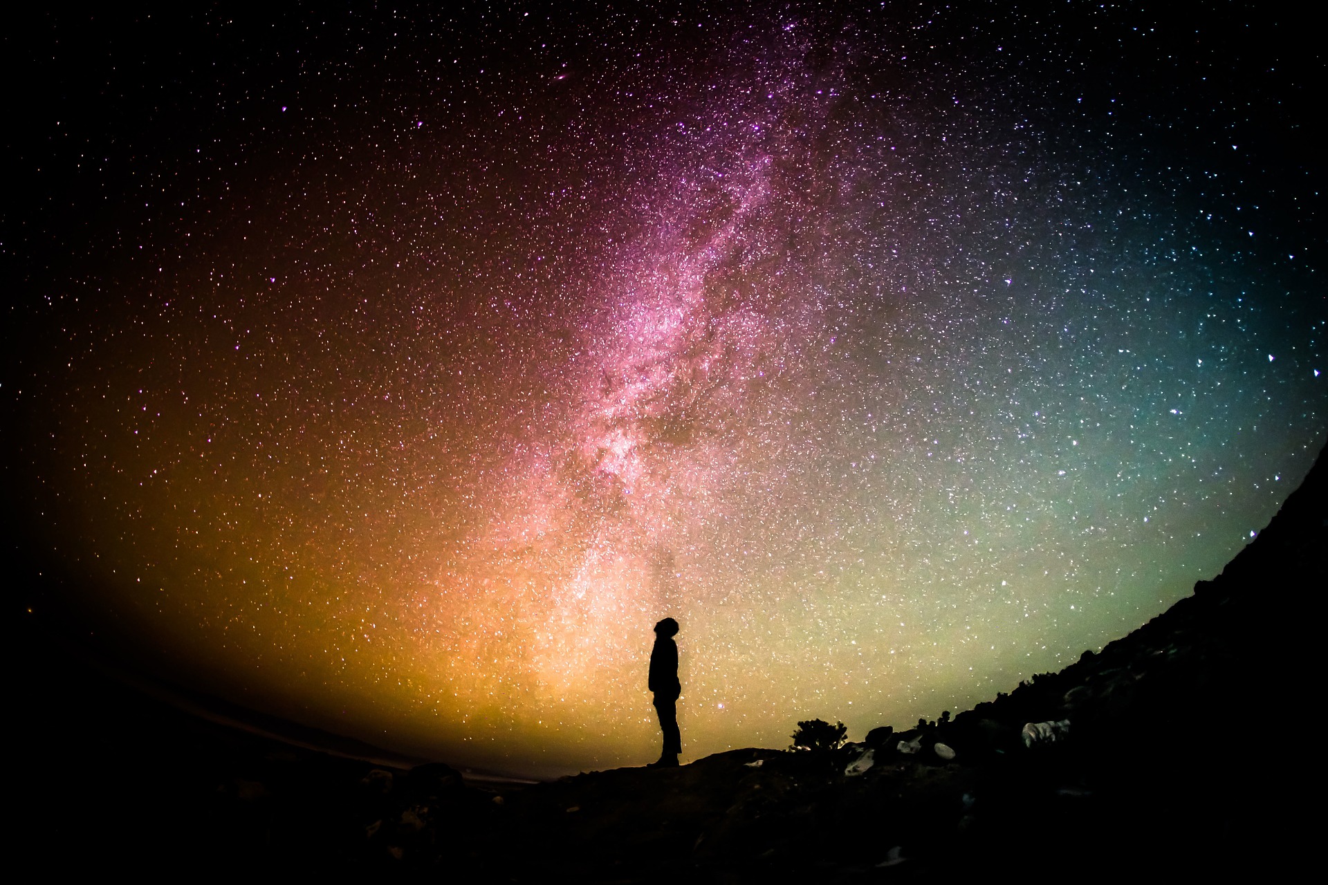 A person looks at a colorful night sky.
