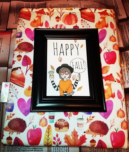 a happy fall sign sitting on top of a book sleeve with fall items on it like leaves and pumpkin pie