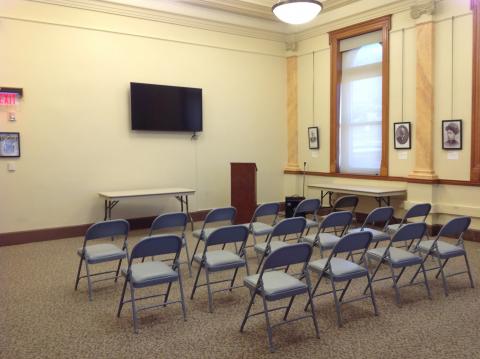 Interior shot of the Owen Meeting Room with chairs arranged auditorium-style with mounted tv at front of room